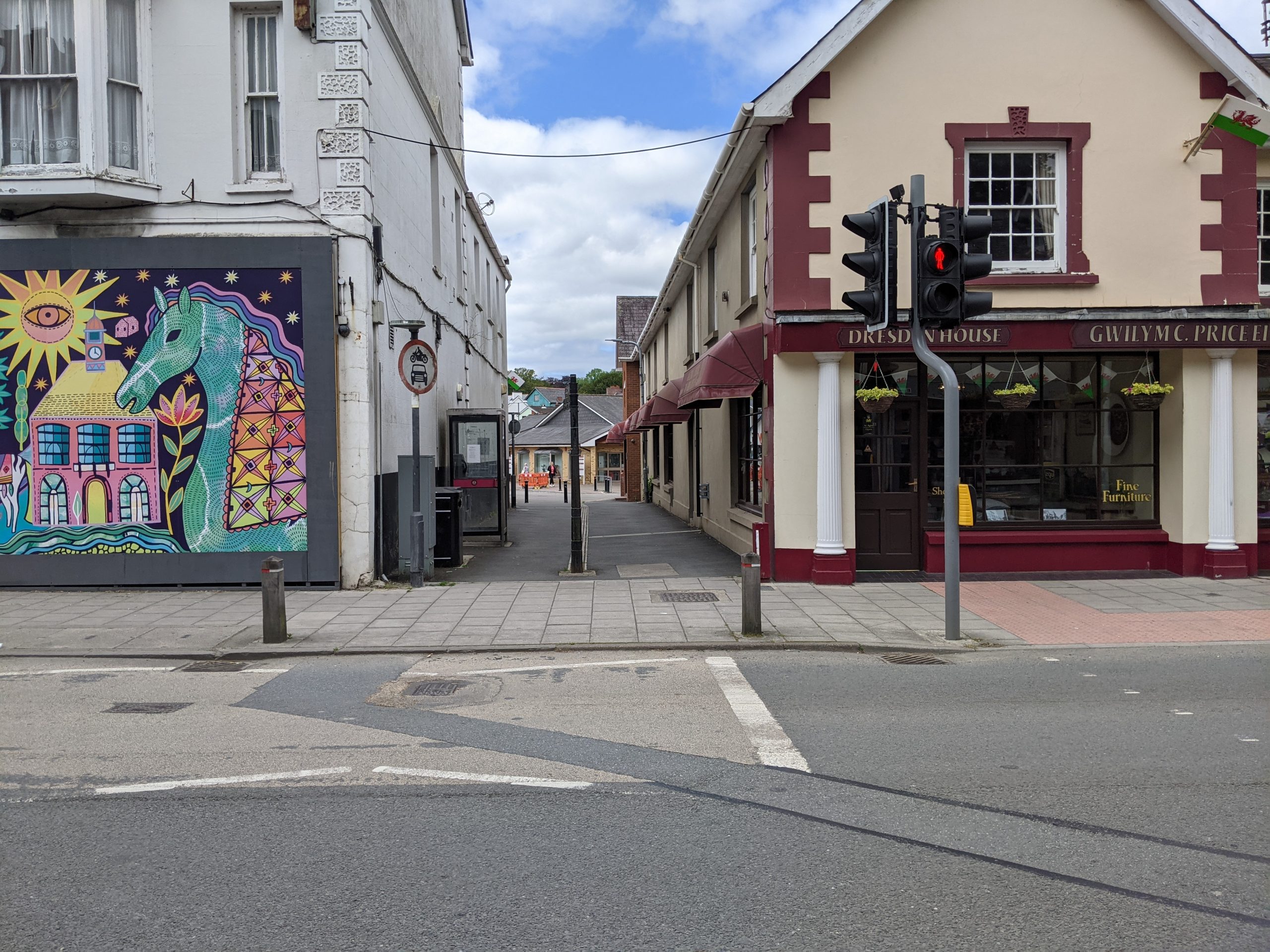 Looking across street to narrower street with colourful historic houses and mural