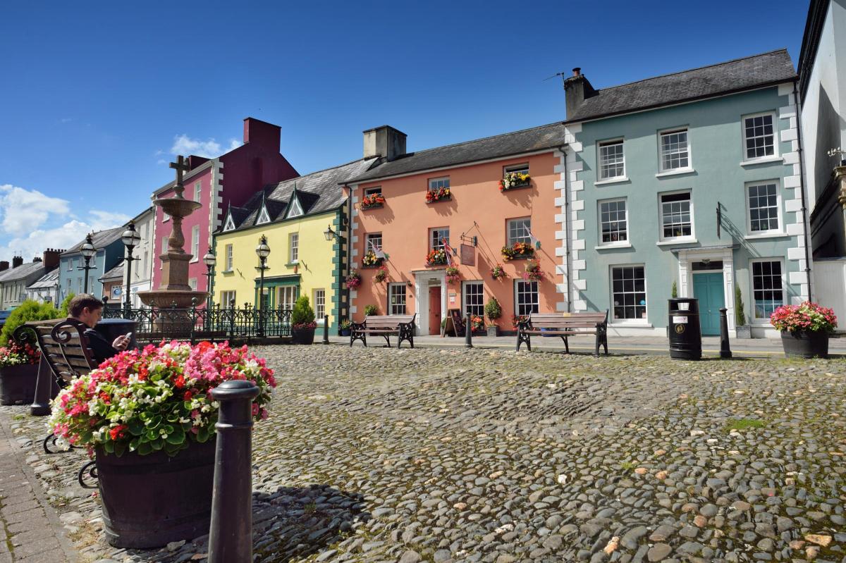 Stone square surrounded by colourful historic buildings and a planter