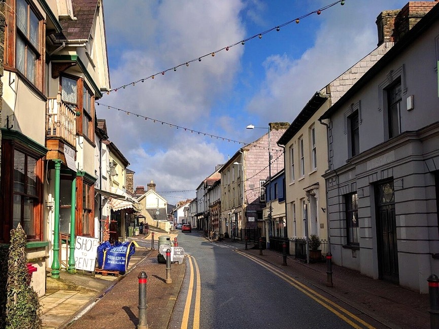 Llandysul high street with shops and signs either side and string lighting above