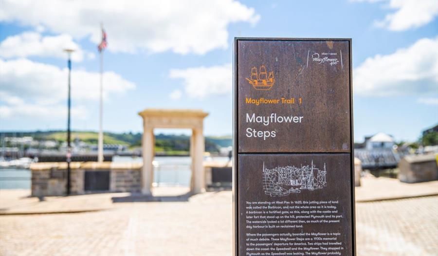 An informational sign made from metal at the Mayflower steps, with the sea in the background