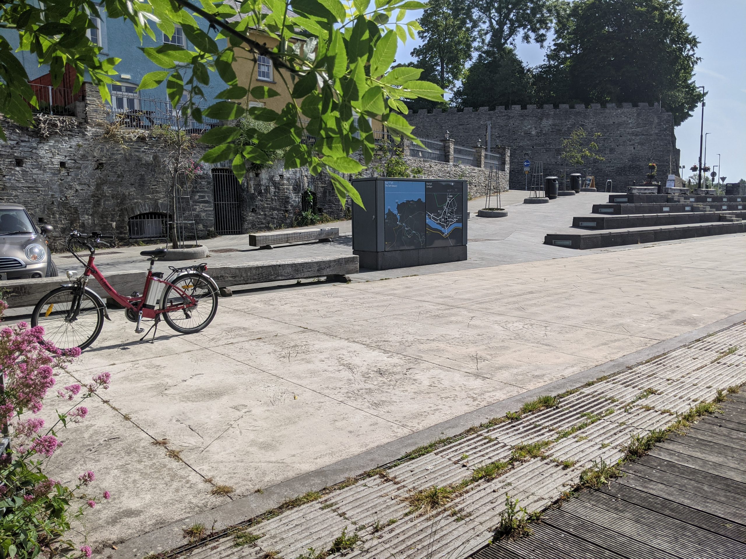 Hard surfacing, tree branches, a bike and stone seating, with a stone wall in the background.